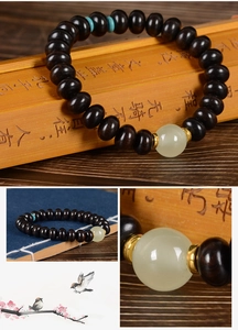 Détail de perles en bois sombre et perle de jade sur un parchemin en bambou