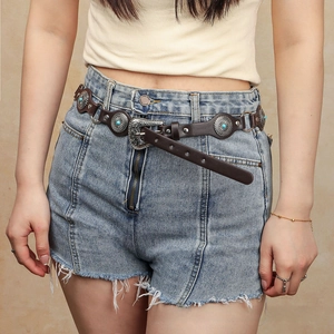 Detail of vintage punk belt with turquoise inlay and retro buckle on brown leather