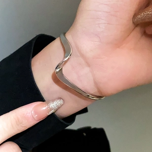 Close-up of minimalist silver wave bangle with polished irregular fluid design