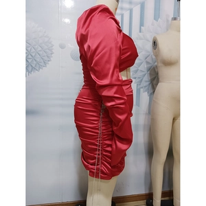 Detail of red satin dress featuring elegant ruching and long sleeves on a mannequin