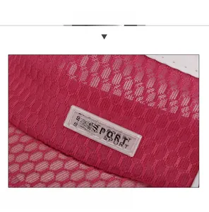 Detailed macro view of pinkish-red mesh fabric and SPORT silicone patch on the baseball cap