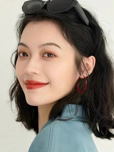 Close-up of model wearing geometric red circular hoop earrings with vintage finish