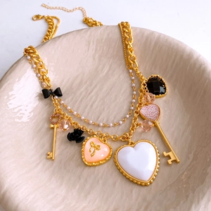 Dettaglio di pendenti vintage a cuore e chiave su collana dorata in piatto ceramico