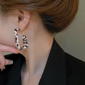 Close-up of model wearing square leopard print resin hoop earrings with gold needles