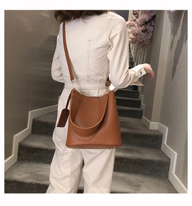 Close-up of brown leather bucket bag showing gold hardware and protective bottom studs