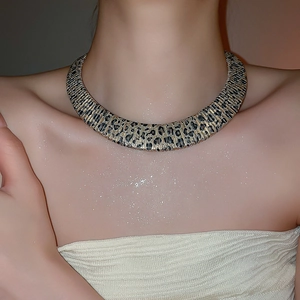 Close-up of golden leopard print metal choker with fine horizontal texture and patterns