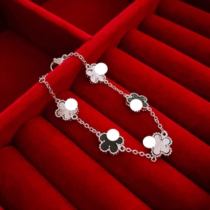 Macro view of five-flower clover bracelet with guilloché pattern and black inlay charms