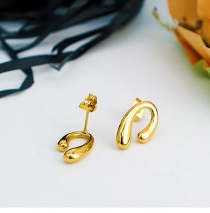 Close-up of polished 18K gold teardrop earrings with organic curved minimalist design