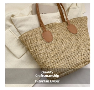 Close-up of beige woven straw tote bag featuring premium brown leather shoulder straps