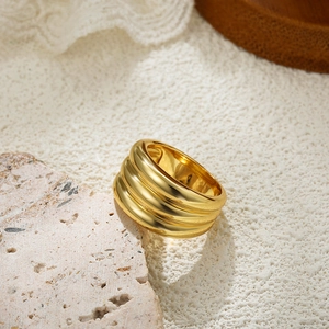 Detailed close-up of a three-layer 18K gold ring on a textured natural stone base