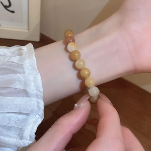 Close-up of beaded amber-colored bracelet worn on wrist over a warm wooden surface