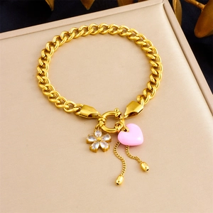 Détail d'un bracelet gourmette doré avec fleur en cristal et pendentifs cœur rose en coffret
