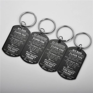 Detail of four black stainless steel dog tag keychains with engraved inspirational quotes