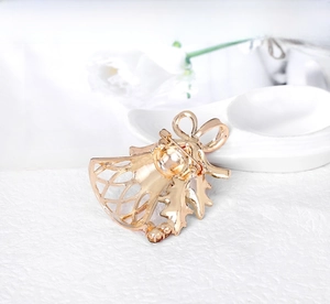 Macro view showing the back pin buckle of a rose gold Christmas bell brooch with rhinestones