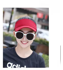 Outdoor close-up of a red woven sun visor hat worn with stylish white frame sunglasses