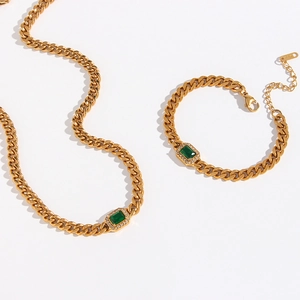Detailed shot of gold Cuban link jewelry set with green gemstone and zircon accents