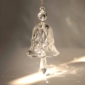 Macro shot of diamond-cut crystal glass wind chime with teardrop pendant and light refraction
