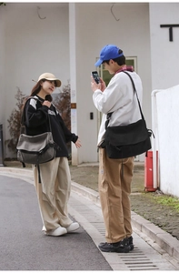 Outdoor shot of black and gray-green canvas messenger bags with adjustable wide straps