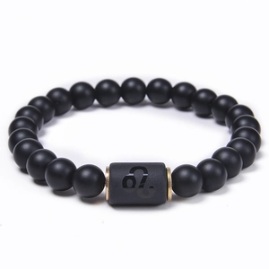 Detail of matte black onyx beads and golden Leo zodiac charm on a beaded bracelet