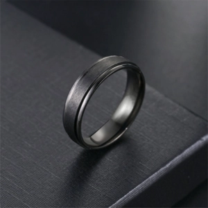 Macro detail of a 6mm matte black titanium steel ring with minimalist grooved edges
