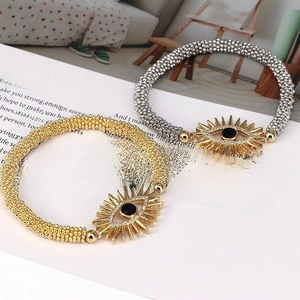 Close-up of gold and silver beaded evil eye bracelets on a poetic white background