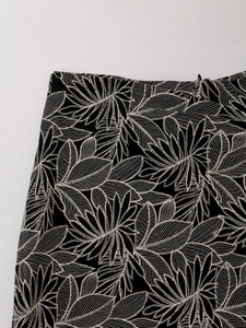 Detail shot of white leaf embroidery craftsmanship on black high-waisted skirt shorts