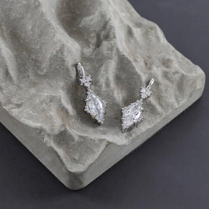 Macro view of marquise-cut crystal earrings on a textured stone base with silver frame