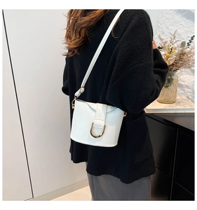 Detailed side view of white bucket bag featuring elegant gold U-shaped metal buckle accent