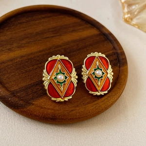 Vue détaillée des boucles d'oreilles vintage avec perle et émail sur plateau bois