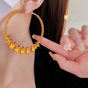 Detail showing amber crystal water drop earrings with large rhinestone hoop design