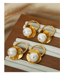 Detailed close-up of 18k gold-plated pearl hoop earrings on a beige silk display