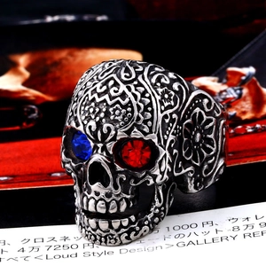 Detailed macro view of a vintage skull ring with red and blue gemstone eyes and floral carvings