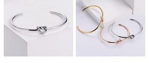 Detail of minimalist knot open bangle in steel, 18k gold, and rose gold finish