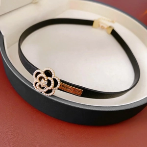 Macro shot of camellia flower buckle with pearls and rhinestones on black leather choker