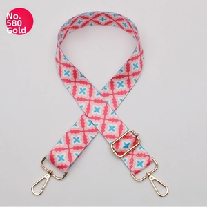 Detail of adjustable polyester bag strap with pink floral pattern and gold metal hooks