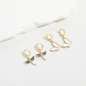 Detailed view of gold dragonfly earrings with blue enamel and sparkling white zircons