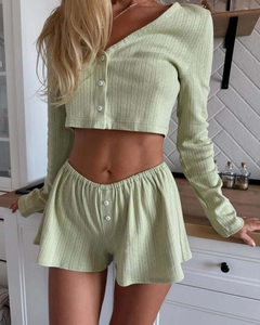 Detail of sage green ribbed knit loungewear set with white buttons in a home setting