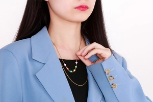 Detail view of gold layered evil eye necklace with colorful enamel charms on model