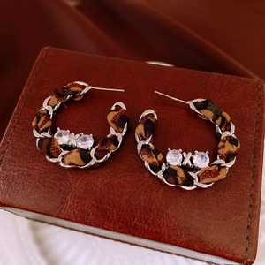 Macro detail of vintage leopard print fabric woven chain earrings with zircon studs
