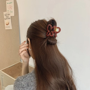Detail of elegant dark red flower hair claw clip with golden metal spring for women