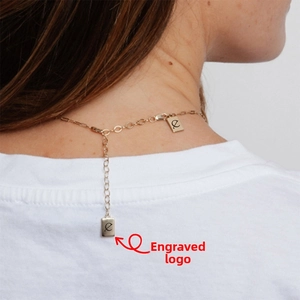Détail du collier réglable en acier titane doré avec deux pendentifs gravés au logo