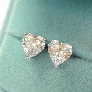 Macro shot of heart-shaped zircon earrings with claw setting in a blue velvet box