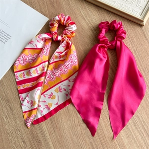 Close-up of pink floral and solid rose silk satin scrunchies with long ribbon ties