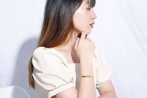 Detail shot of a minimalist slim gold C-shaped open cuff bracelet on a female wrist