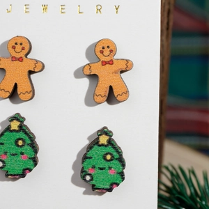 Macro detail of wooden gingerbread man and Christmas tree stud earrings on a display card
