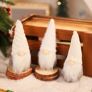 Detailed view of three white and grey knitted Christmas gnomes on a rustic wood base