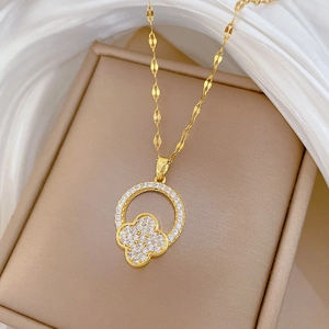Close-up of gold titanium necklace with sparkling crystal clover pendant on silk
