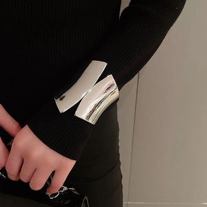 Close-up of wide polished silver metal cuff bracelet styled over a black sleeve