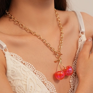 Detailed macro view of vibrant red resin cherry pendants on a golden OT clasp chain
