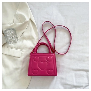 Détail du sac bandoulière en cuir PU rose avec motif cœur gaufré et finitions dorées